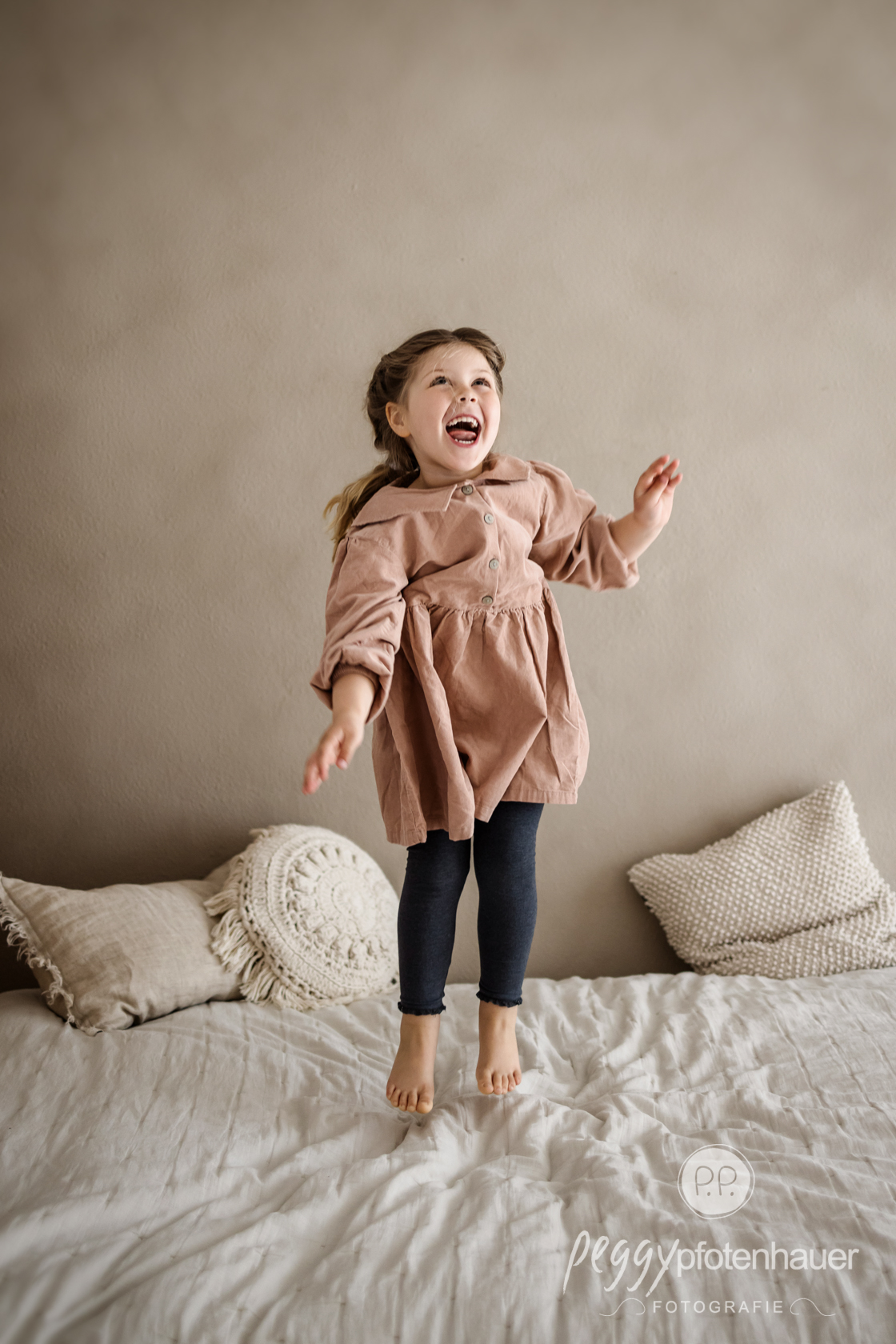 ausgelassen auf dem Bett springendes Mädchen