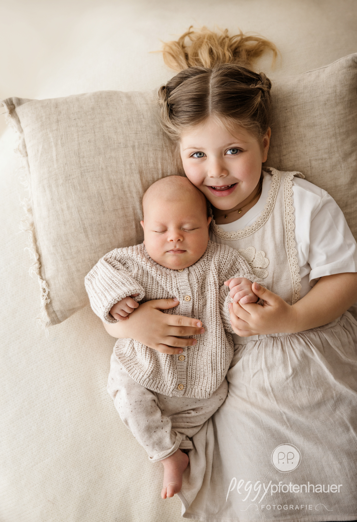 große Schwester kuschelt mit Baby