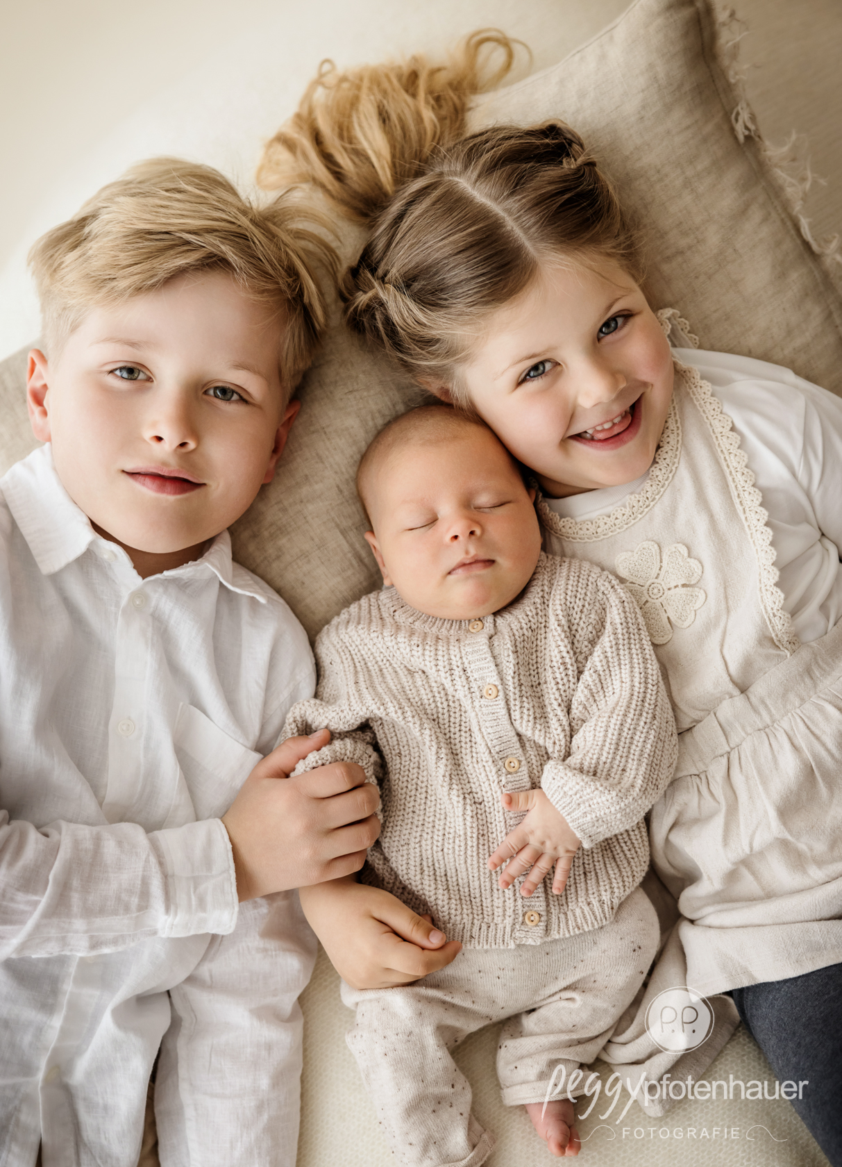 Geschwister mit Baby kuschelnd