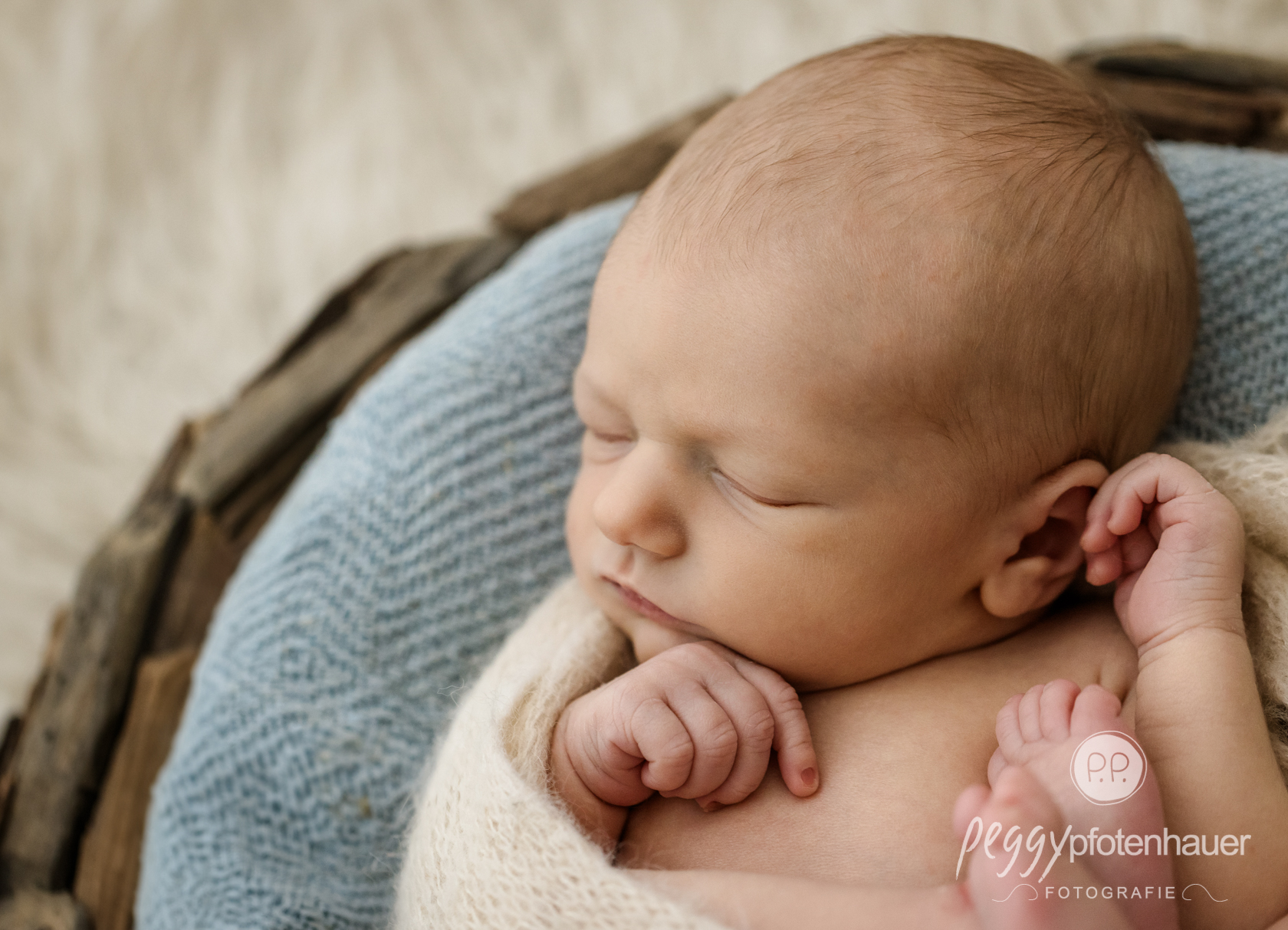 neugeborenenfotografie-bayern Baby liegt eingekuschelt in Decke