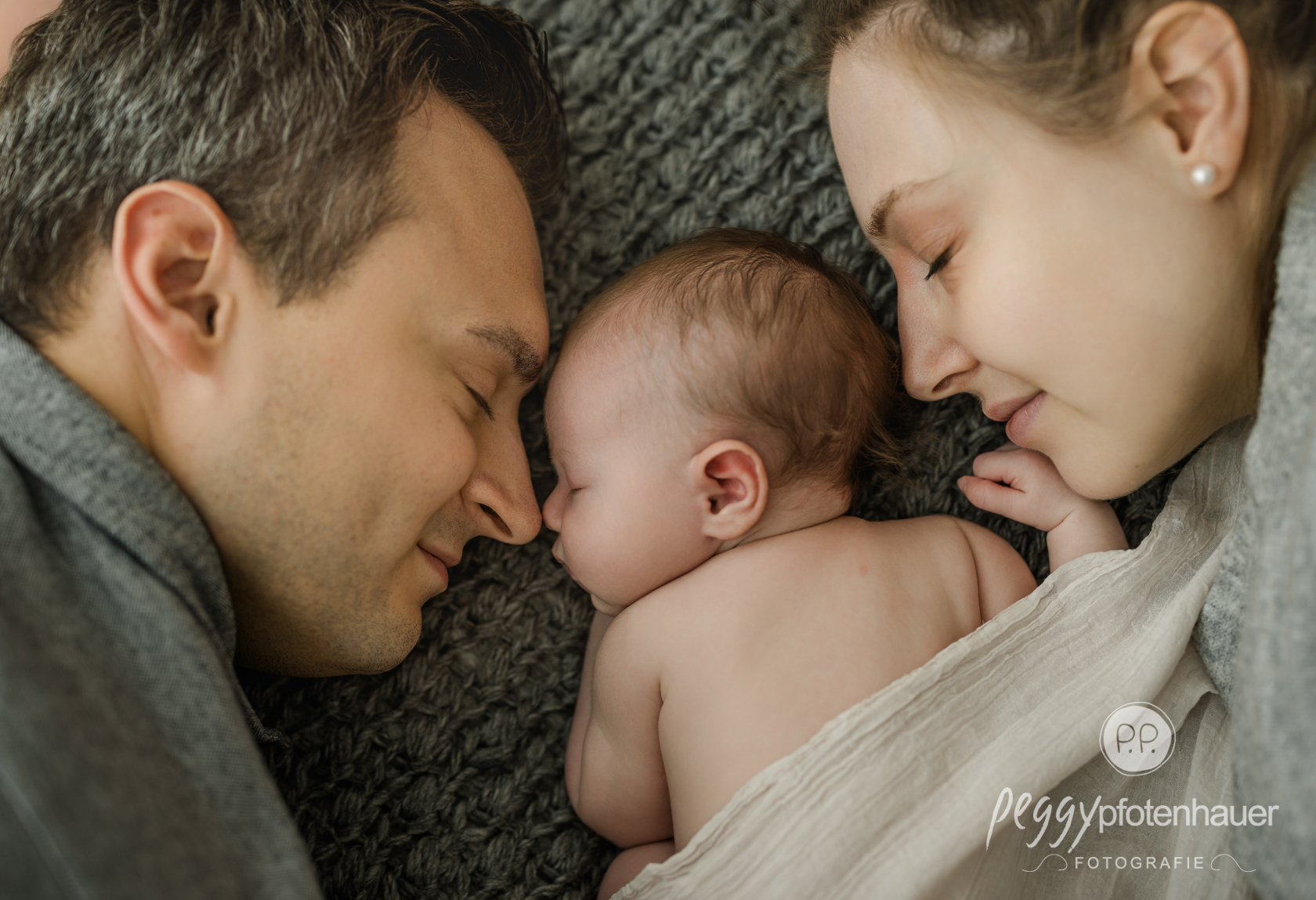 newbornfotografin-wuerzburg Mama und Papa mit Baby auf Bett kuschelnd