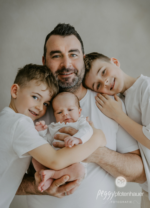 Papa kuschelt mit Kindern und Baby