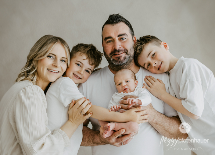 Familie mit drei Kindern steht zusammen und freut sich