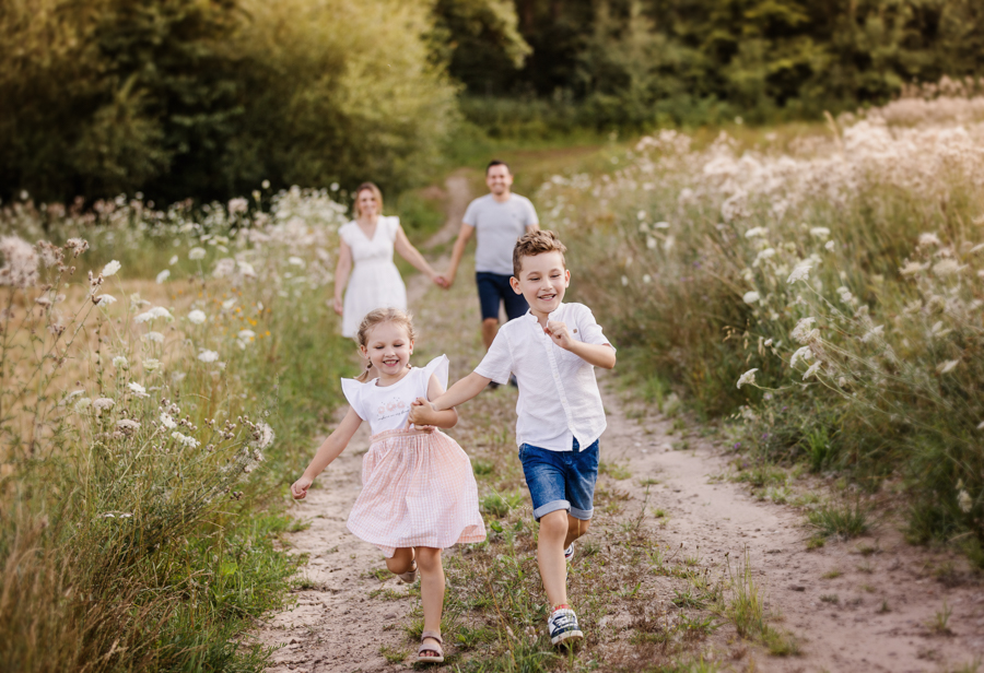emotionale-familienfotografie-nuernberg Familie rennt im Abendlicht in Nürnberg über Wiesenweg und hat Spaß