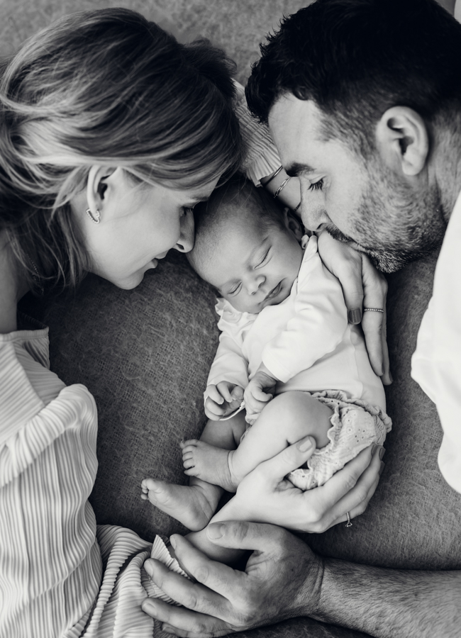 Mama und Papa liegen mit Baby in der Mitte auf Bett
