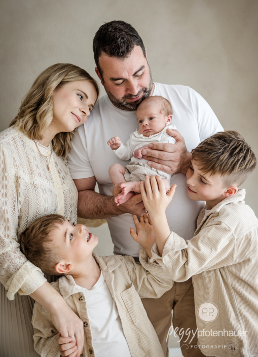 Familie mit drei Kindern steht ganz nah beieinander und schaut sich gegenseitig an