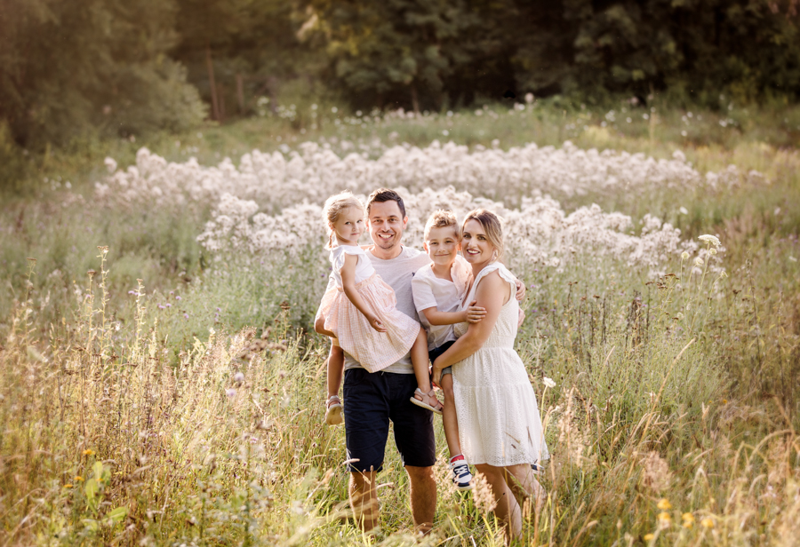 familienfotos-in-der-natur-bamberg Familie steht in einer Sommerwiese im Abendlicht und hat Spaß