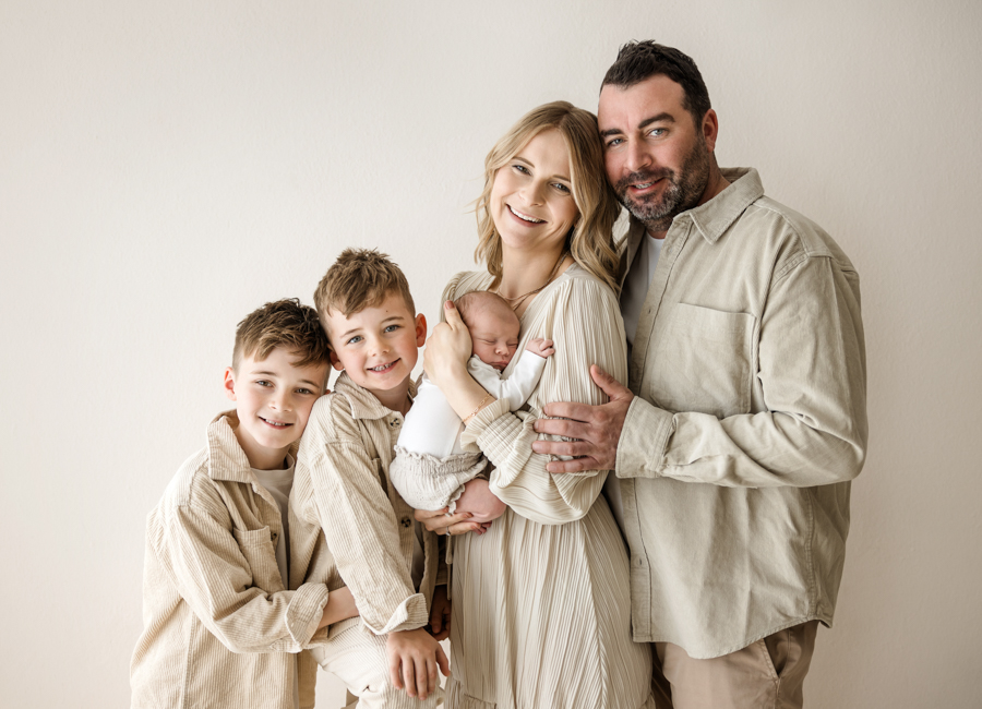 Familie mit drei Kindern steht nebeneinander und lacht