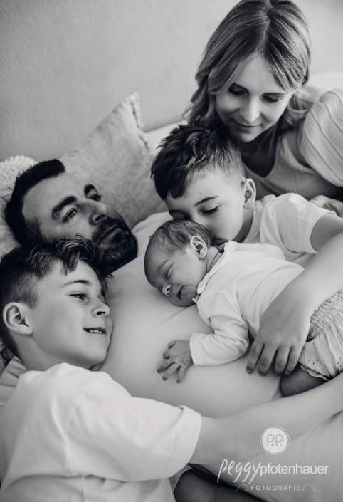 Baby und Familie kuschelt auf Papa auf Bett