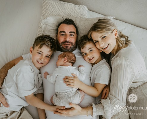 Familie mit Baby liegt auf Bett und ist glücklich