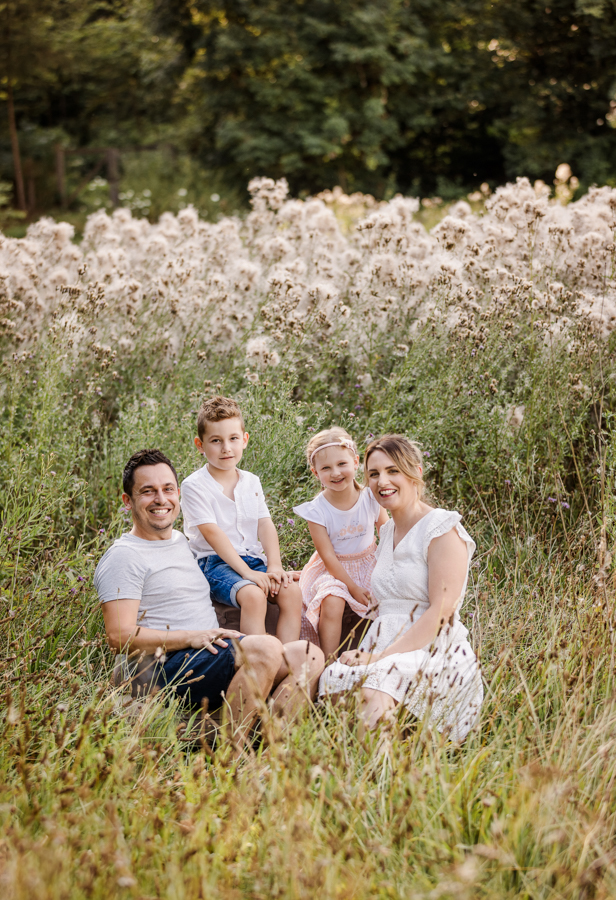 familienfotoshooting-outdoor Familie sitzt auf einem Sofa in einer Wiese und hat Freude