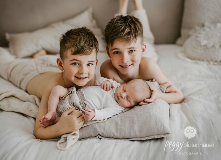 Brüder kuscheln mit neuem Baby