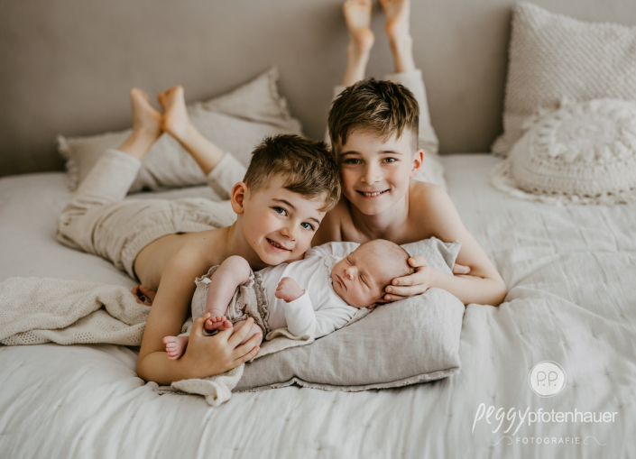 Brüder halten Baby auf Arm und sind glücklich