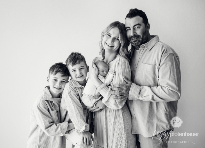 Familie mit drei Kindern steht zusammen und freut sich