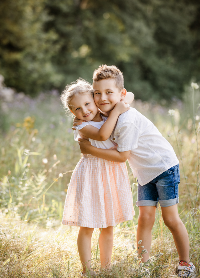 Geschwister stehen auf Wiese in Hirschaid und umarmen sich und lachen