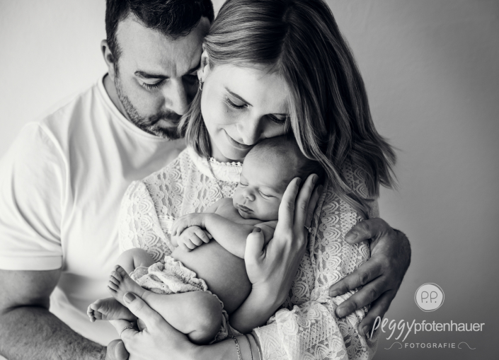 Mama und Papa halten Baby und sind emotional