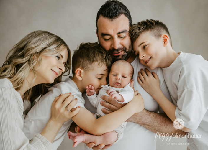 Familie mit Baby steht eng zusammen und kuschelt