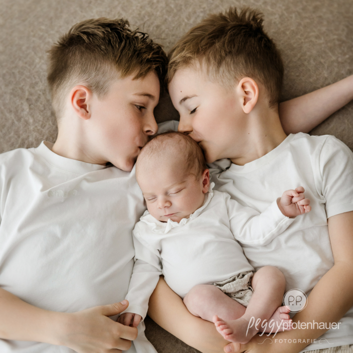 Geschwister küssen Baby