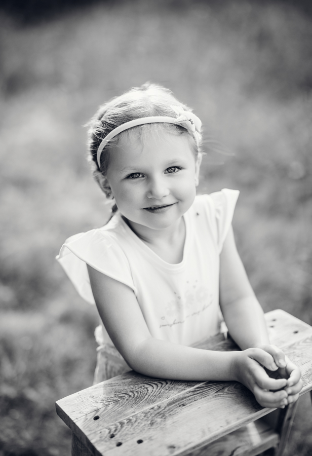 Mädchen steht auf Wiese im Abendlicht und freut sich