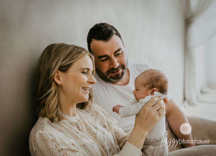 Mama und Papa halten Baby und sind glücklich
