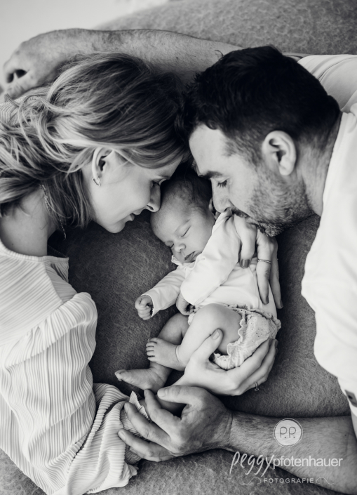 Mama und Papa schlafen auf Bett und Baby liegt in der Mitte