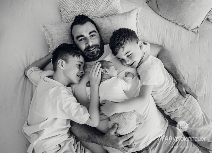 Baby und Geschwister kuscheln auf Papa