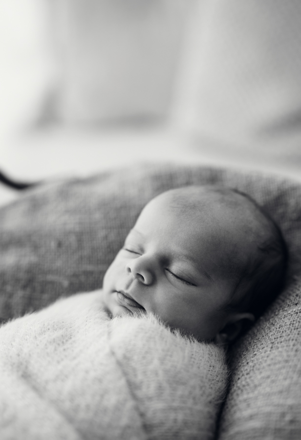 Baby ist in Decke eingekuschelt und schläft in Körbchen