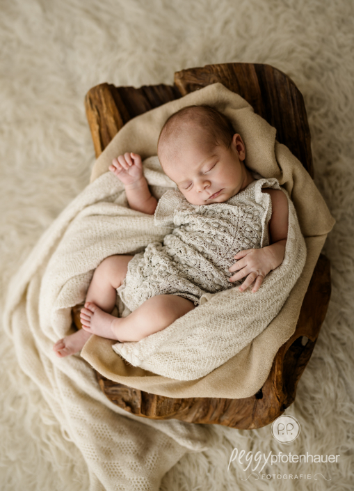 Baby liegt eingekuschelt in Schale