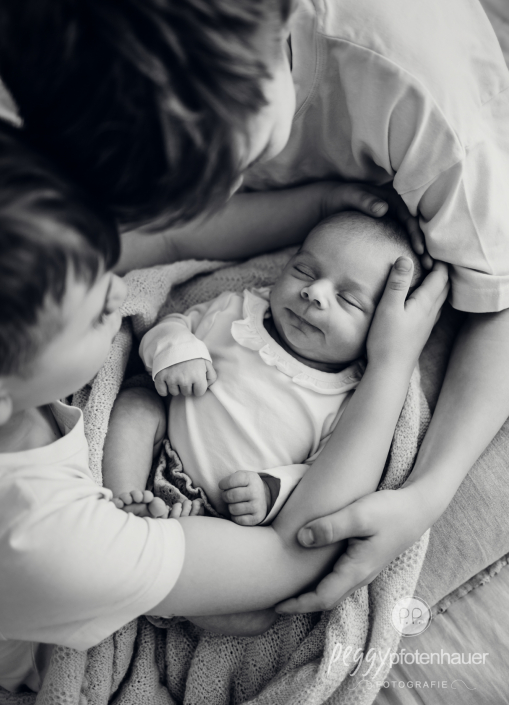 Baby liegt auf Schoß von Brüdern und schläft