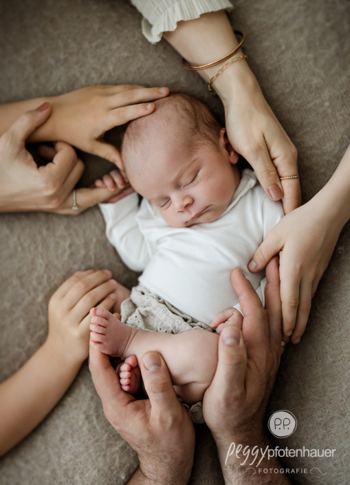 Baby wird von vielen Händen gehalten