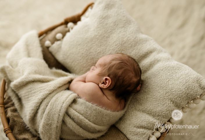 Baby liegt eingerollt in Körbchen