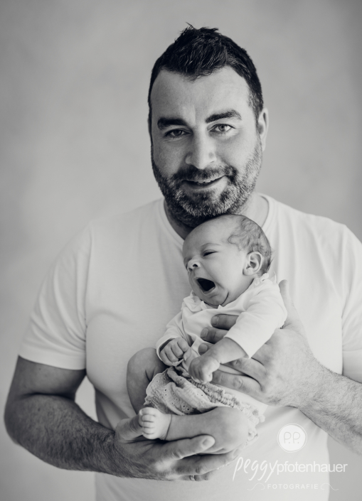 Papa kuschelt mit gähnendem Baby