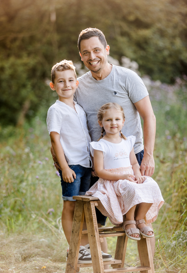 papa-kind-fotos Papa und Kinder stehen in Wiese im Abendlicht und haben Spaß