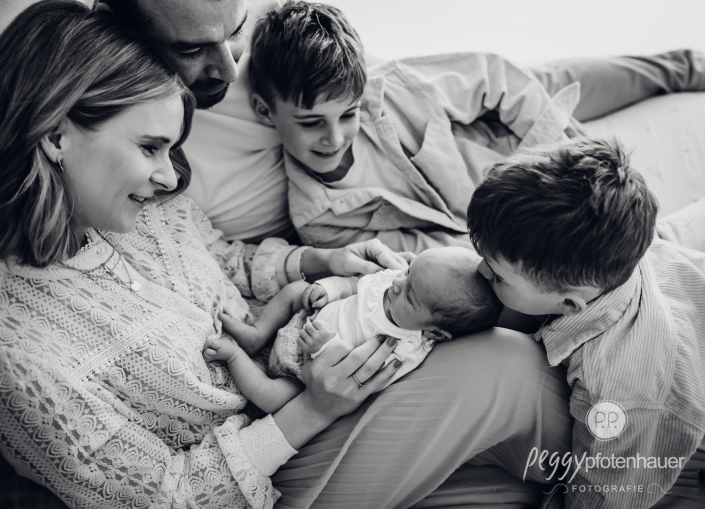 Familie sitzt auf Bett und kuschelt