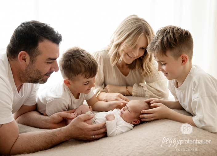 Familie sitzt um Baby herum und freut sich