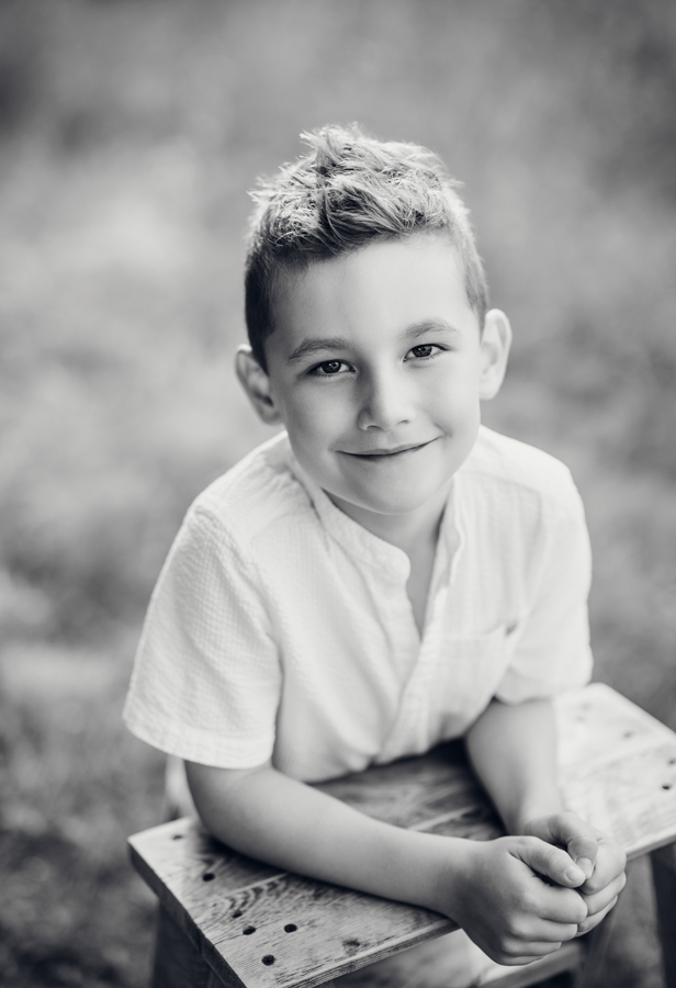 Junge steht auf Wiese im Abendlicht und lacht