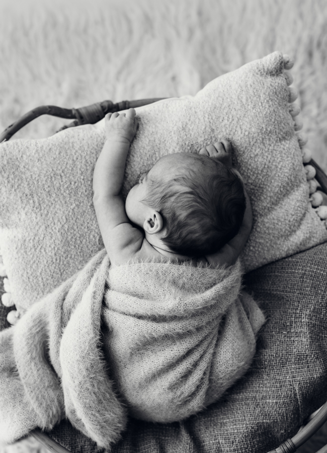 Baby hängt entspannt in Körbchen und schläft