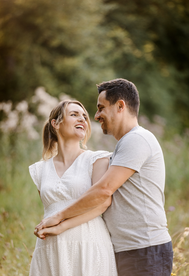 professionelle-paarfotos-wuerzburg Paar steht auf Wiese und lacht sich verliebt an