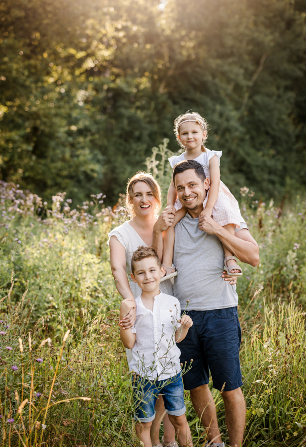 ungestellte-familienfotos-nuernberg Familie steht im Abendlicht auf einer Wiese in Nürnberg und hat Spaß