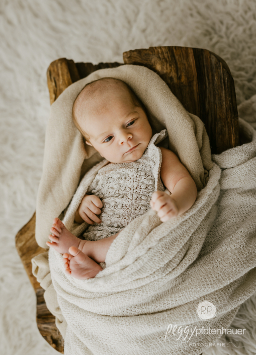 Neugeborenes liegt wach in Körbchen