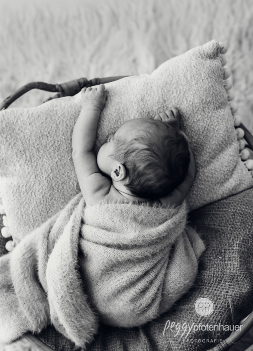 Baby hängt in Körbchen und schläft entspannt