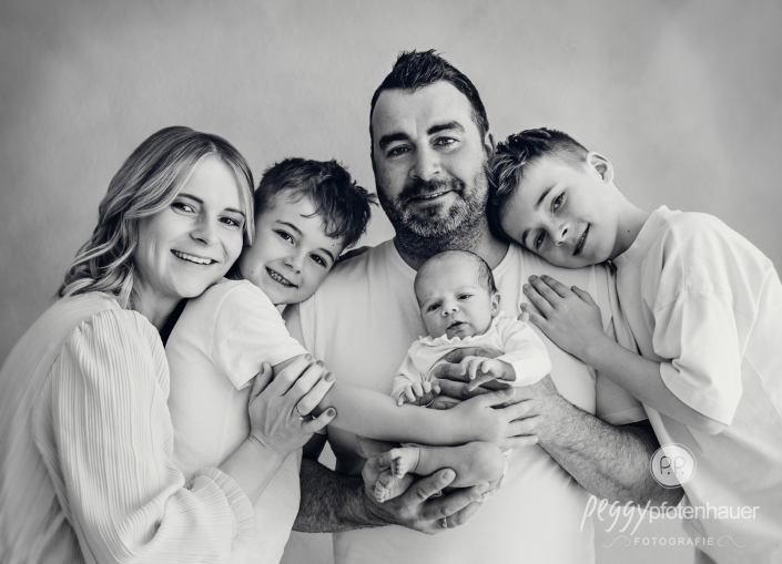 Familie steht mit Baby in Papas Armen und ist glücklich