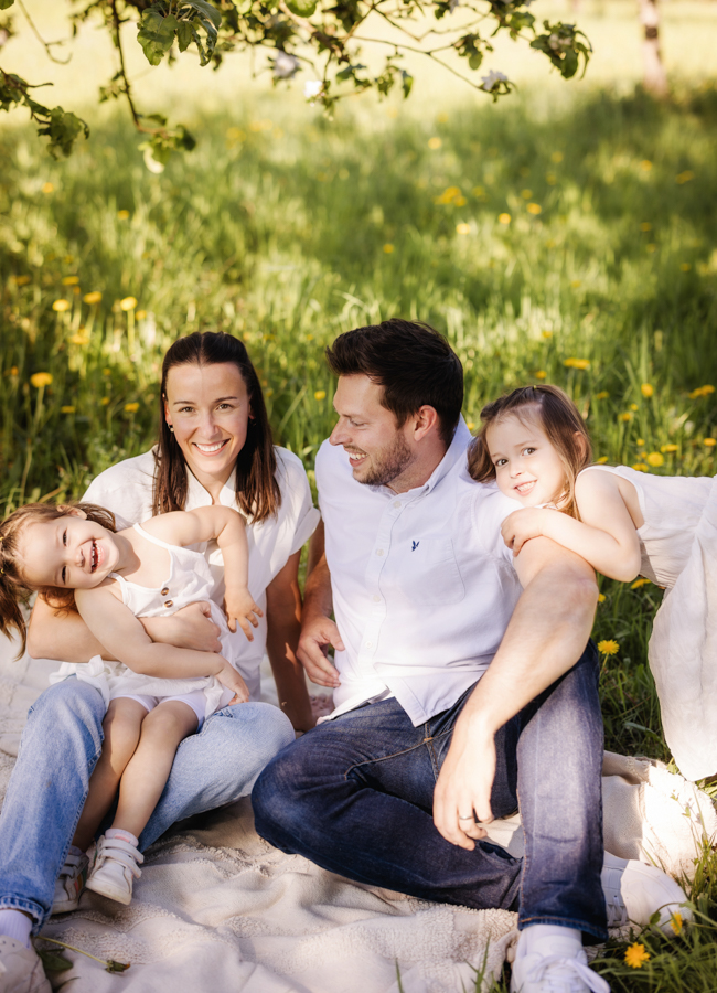 Familienfotograf-Hassfurt Familie sitzt auf Decke in Frühlingswiese und spielt und hat Spaß