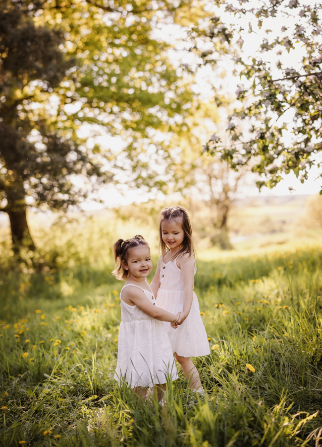 zwei Mädchen tanzen in einer Wiese Hand in Hand