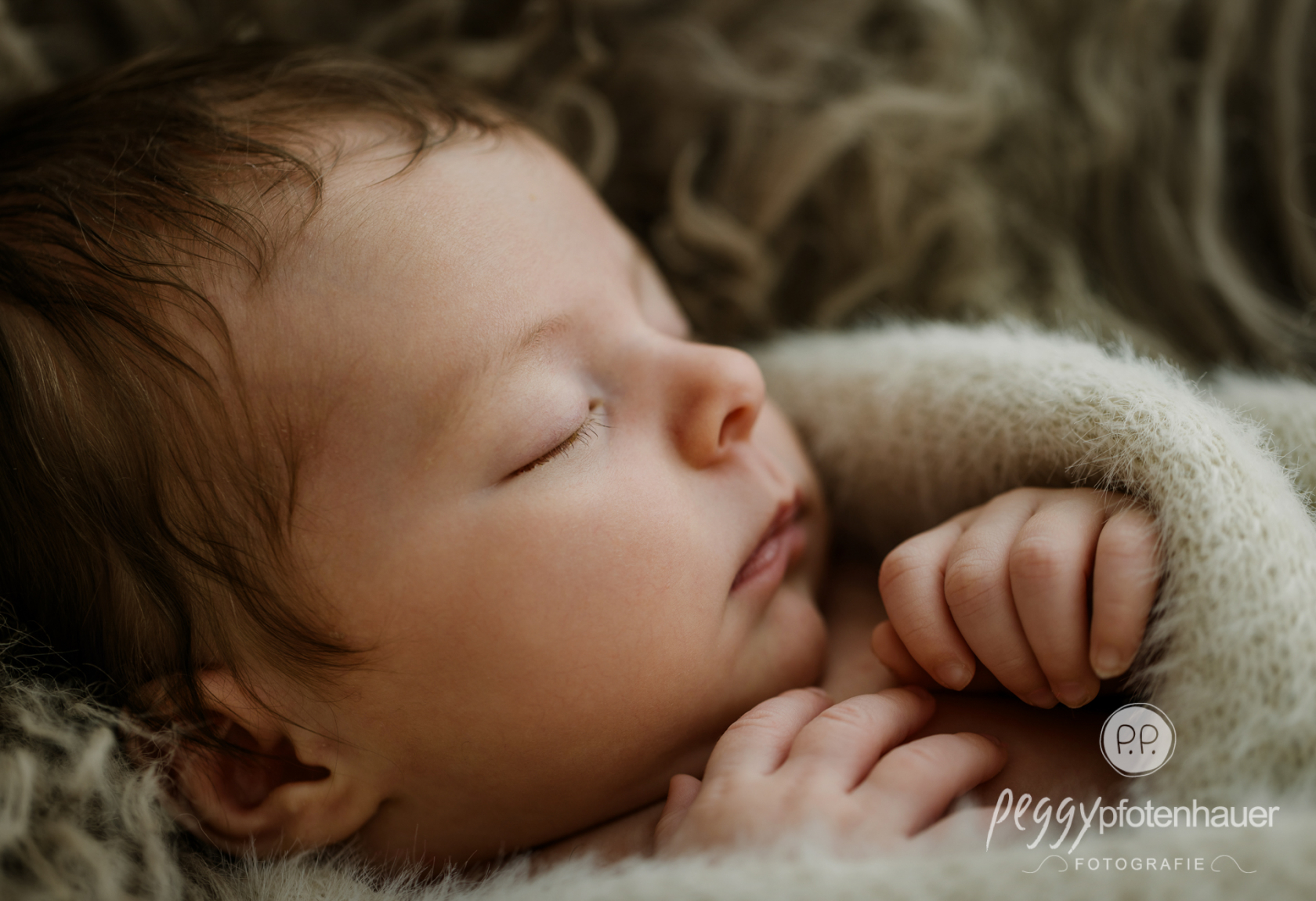 Baby liegt liebevoll eingekuschelt in Decke und schläft