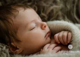 Baby liegt liebevoll eingekuschelt in Decke und schläft
