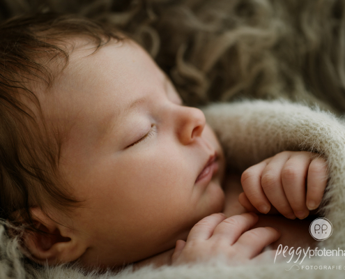 Baby liegt liebevoll eingekuschelt in Decke und schläft
