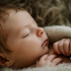 Baby liegt liebevoll eingekuschelt in Decke und schläft