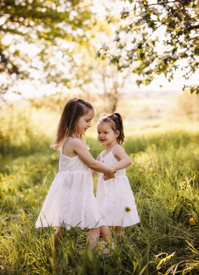zwei Kinder tanzen Hand in Hand in einer Wiese