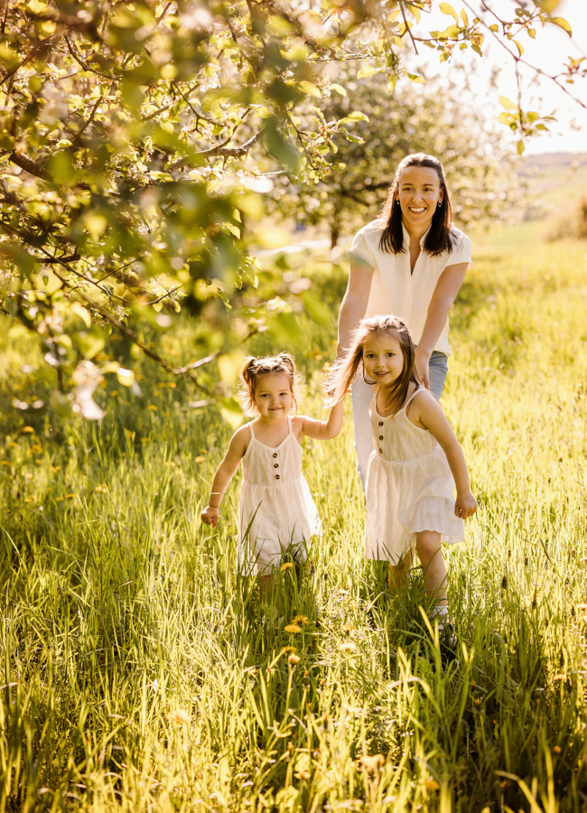 professionelle-Familienfotos-Hassfurt Mama rennt mit Kindern durch Frühlingswiese in der Sonne und alle haben Spaß